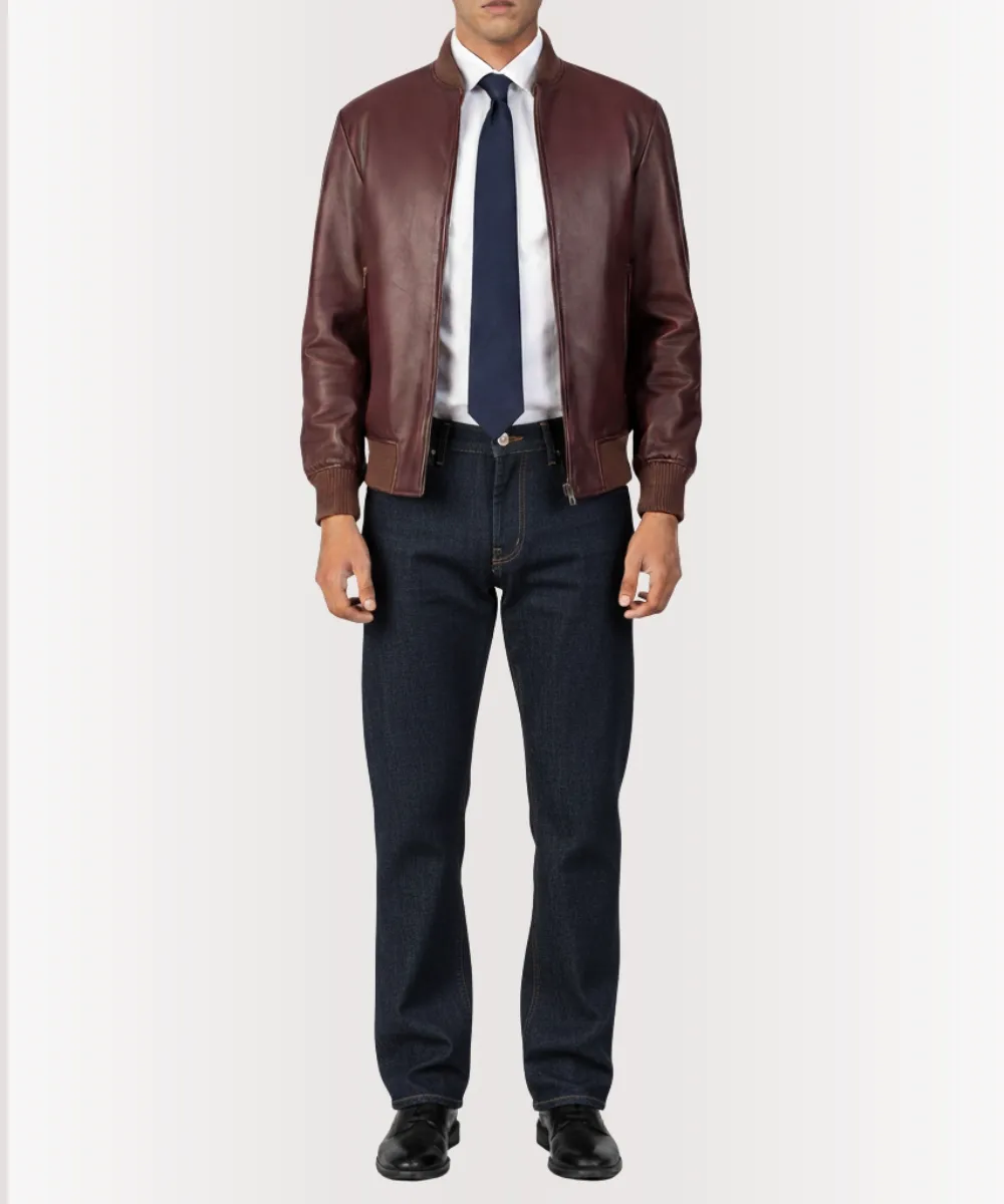 Model styling a burgundy leather jacket mens outfit with jeans and boots in an urban street background.