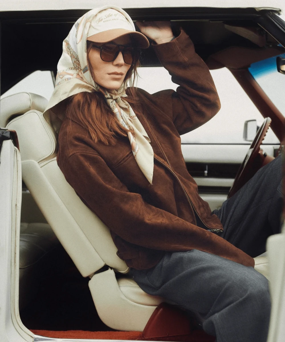 Side view of a women in a brown suede leather jacket, showing relaxed fit and smooth suede texture in daylight.