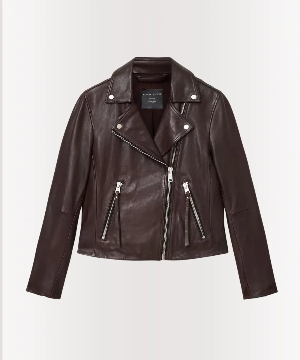 Woman sitting in jeans and oxblood leather jacket, relaxed pose with soft natural lighting.