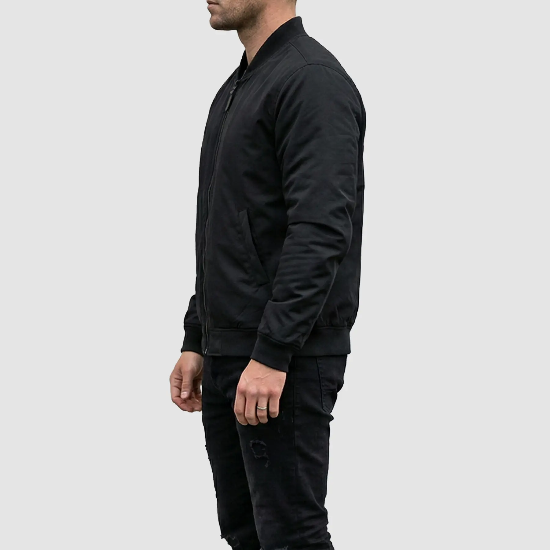 Man wearing a black bomber jacket with casual streetwear outfit, styled with jeans and sneakers.